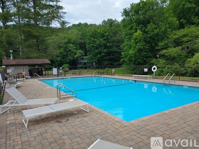 A pool surrounded by trees and a small building.