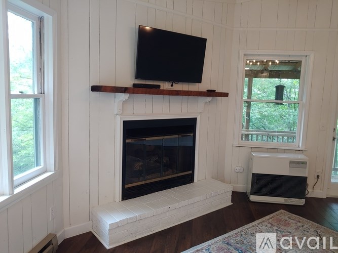A white fireplace with a black screen tv above it.