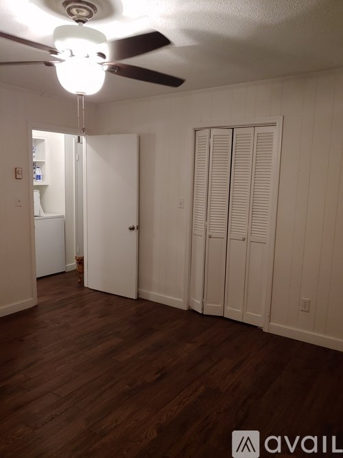 A room with a ceiling fan and wooden floors.
