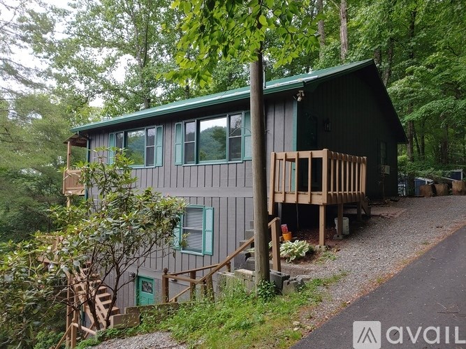 A house with a green roof is surrounded by trees.