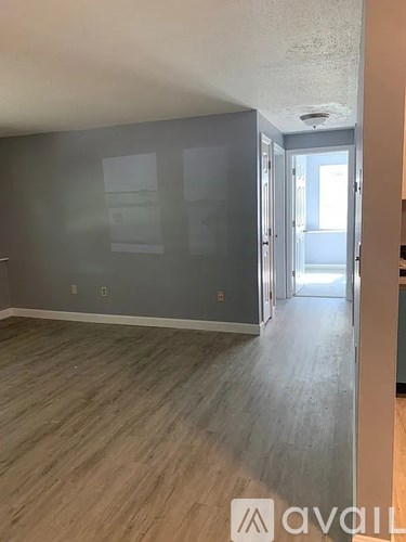 A room with wooden flooring and a doorway leading to another room.