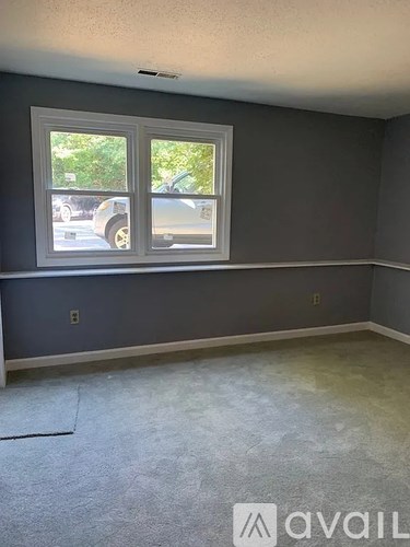 A room with a grey wall and a window.