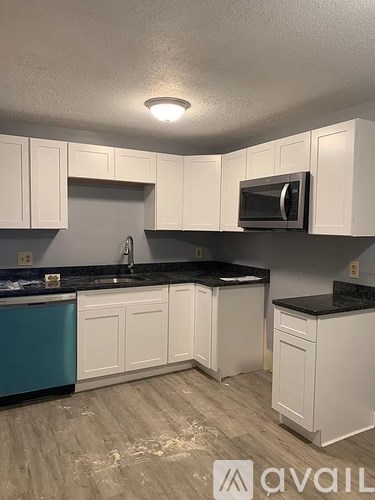 A kitchen with white cabinets and a black countertop.