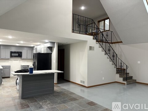 A modern kitchen with a bar and a staircase.