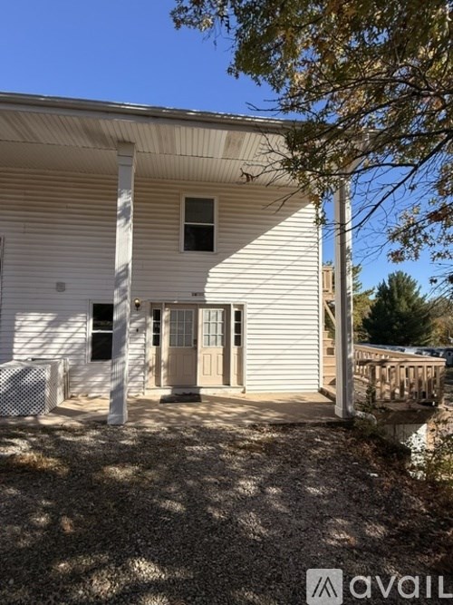 A white house with a brown door and a fence in front.