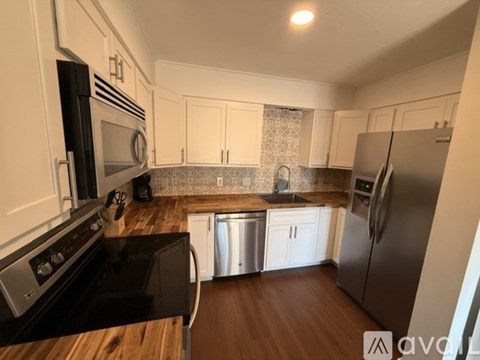 A kitchen with black appliances and white cabinets.