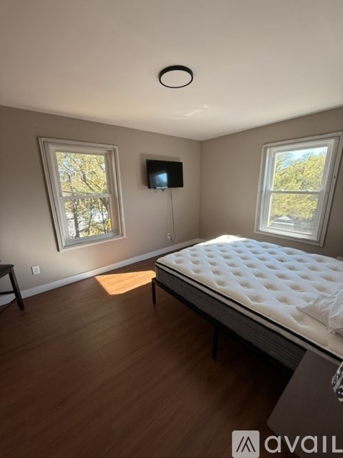 A bedroom with a bed, a window, and a TV mounted on the wall.
