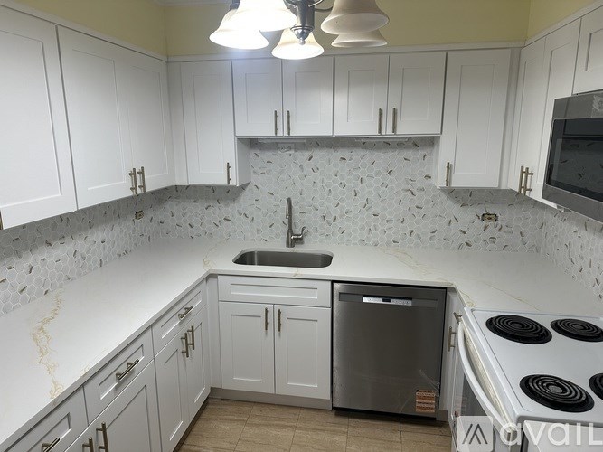 A kitchen with white cabinets and a tiled backsplash.