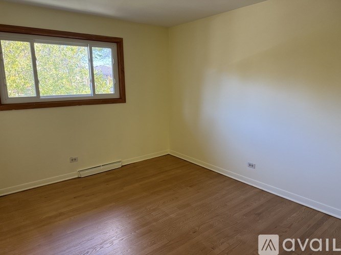 A room with wooden flooring and a window letting in natural light.