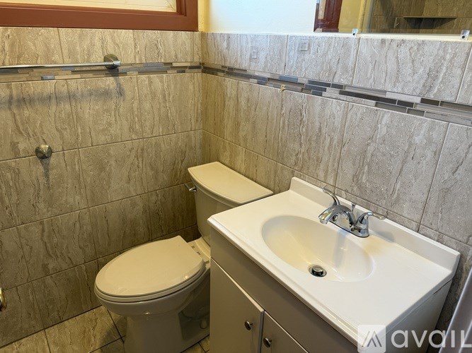 A bathroom with a toilet, sink, and tiled walls.