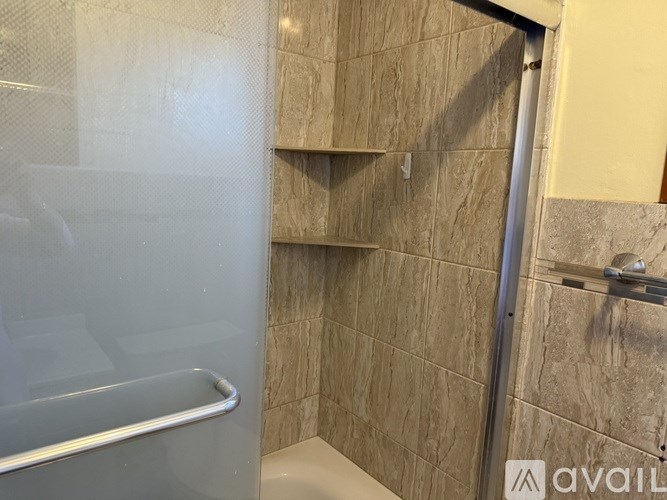 A bathroom with a glass shower door and tiled walls.