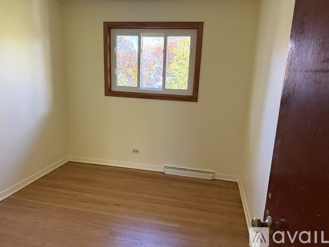 A room with a window showing a view of trees.