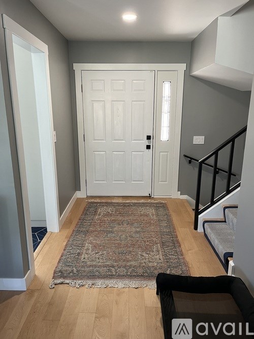 A hallway with a rug and a door.