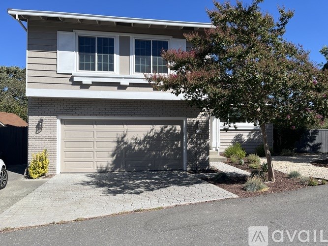 A house with a garage and a tree in front.