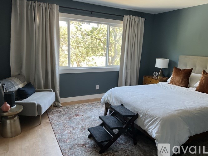 A bedroom with a large bed and a window with curtains.