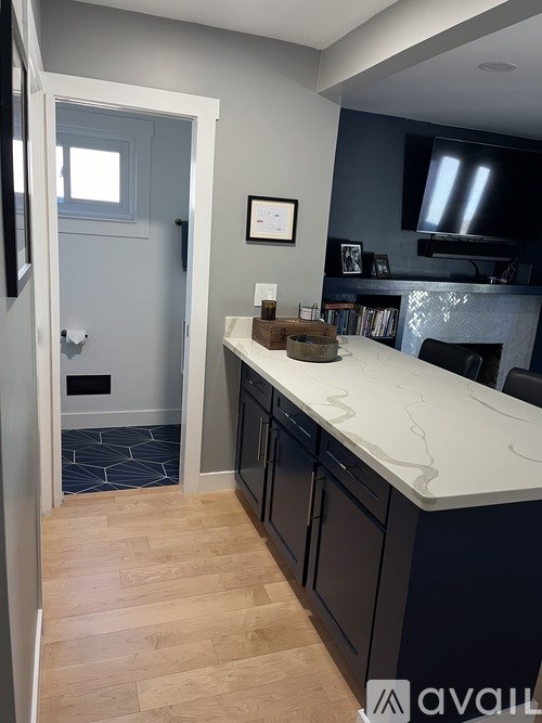 A kitchen with a white counter top and wooden floors.
