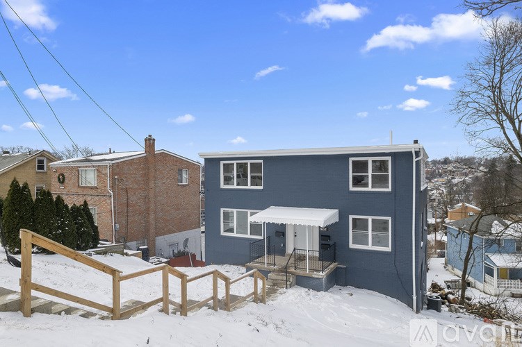 A blue house with a white awning and a wooden fence in the snow.