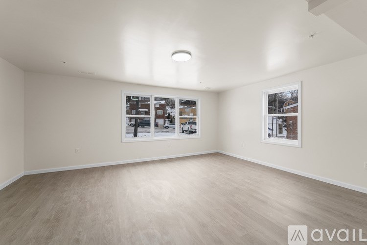 A spacious room with wood flooring and two framed pictures on the wall.