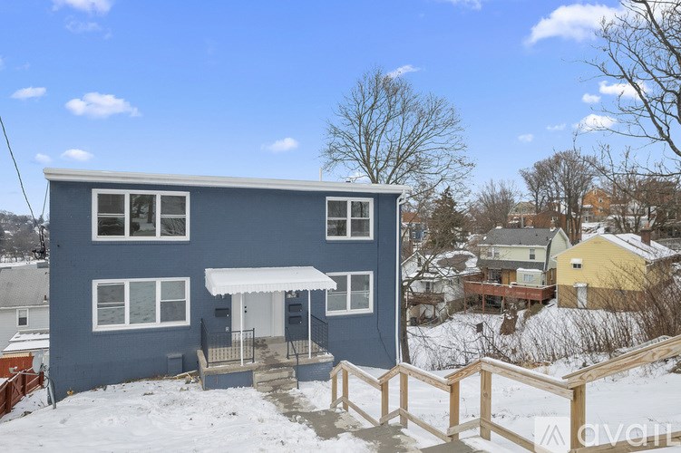 A blue house with a white awning and a wooden fence in front.