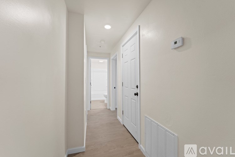 A long hallway with a white door and a wall-mounted thermostat.