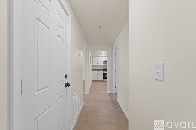 A long hallway with a white door on the left and a light switch on the wall.