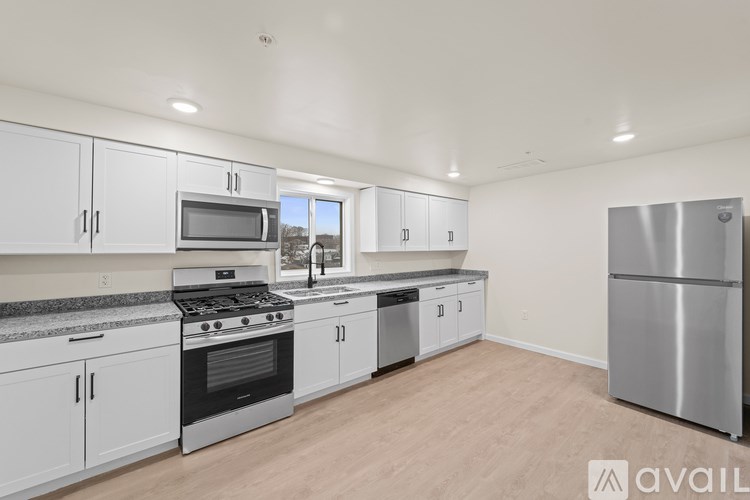 A kitchen with white cabinets and stainless steel appliances is available for rent.