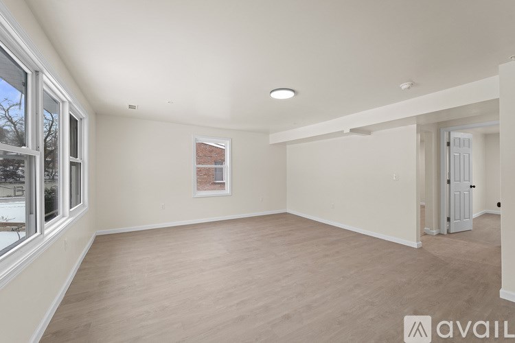 A spacious room with wooden flooring and white walls.