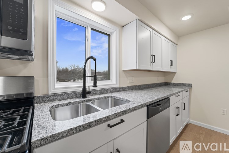 A kitchen with a sink, stove, and window.
