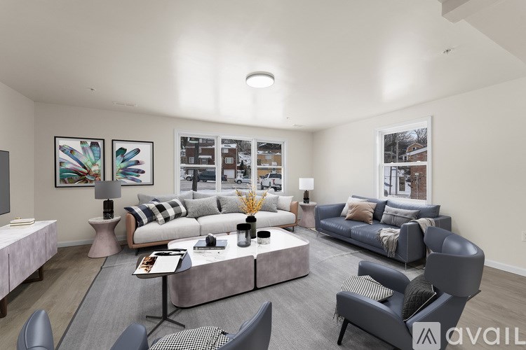 A living room with a grey couch, a grey chair, a grey coffee table, a pink table, a painting, a lamp, and a window.