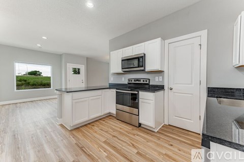 A kitchen with white cabinets and a wooden floor.