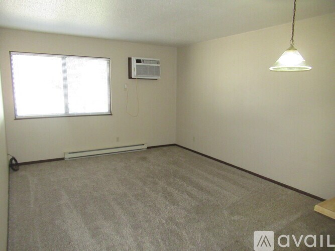 A room with a carpeted floor, a window, a ceiling fan, and a wall-mounted air conditioner unit.