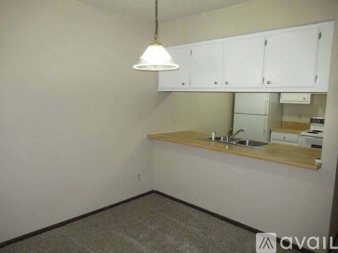 A kitchen area with a sink, cabinets, and a light fixture.