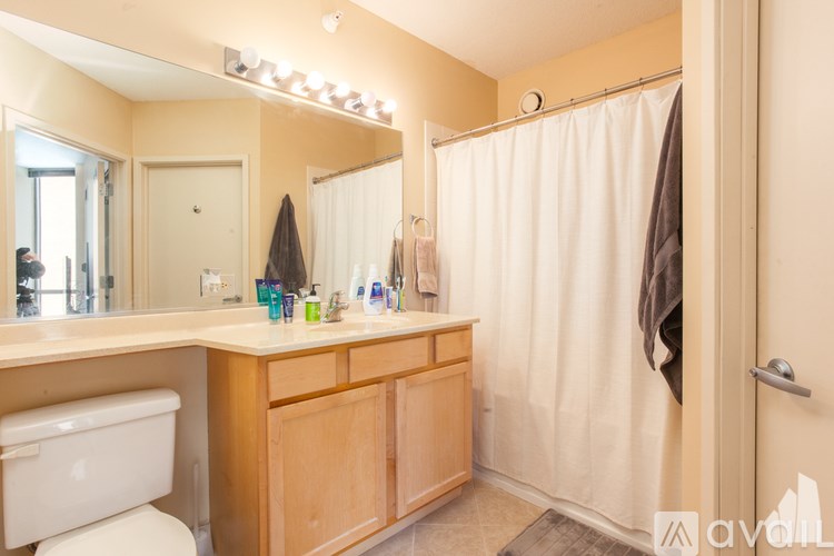 A bathroom with a white toilet, wooden vanity, and a shower with a white curtain.