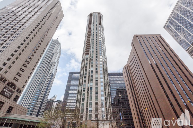 A tall building stands in front of a cluster of other buildings.