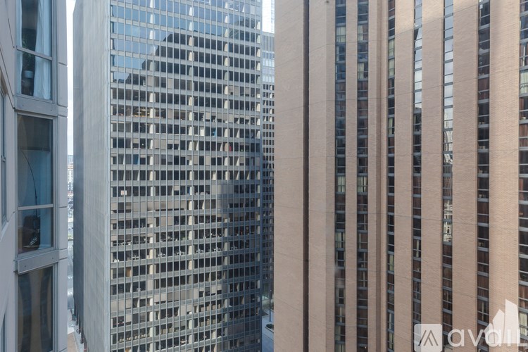 A tall building with a grid of windows is reflected in the glass of a building in front of it.