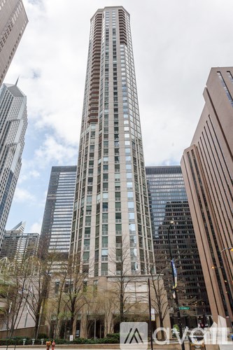 A tall building with a lot of windows stands in front of other buildings.
