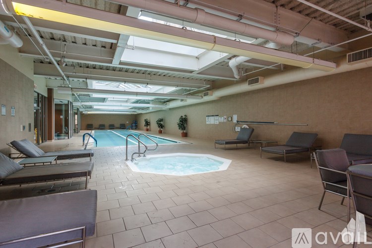 A large indoor swimming pool with lounge chairs and a tiled floor.