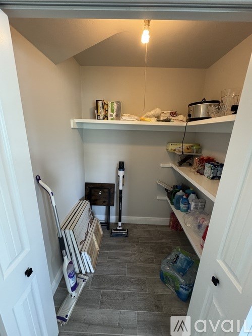A small, empty kitchen with a white door and a white shelf.