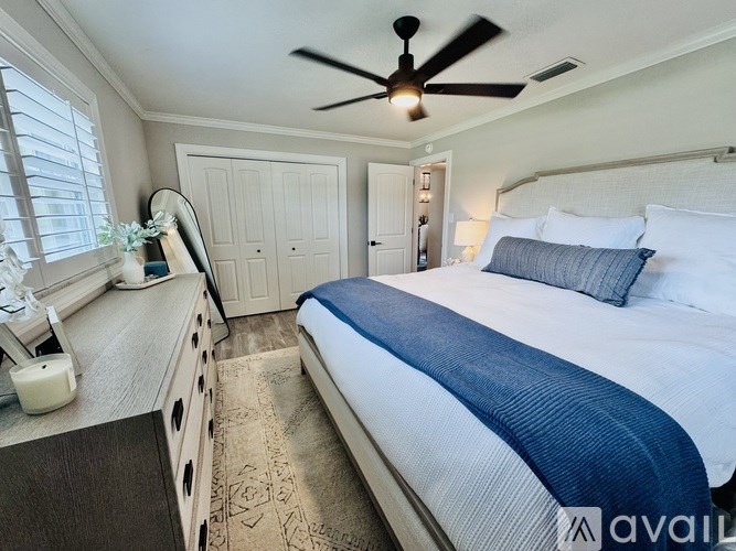 A bedroom with a large bed and a ceiling fan.