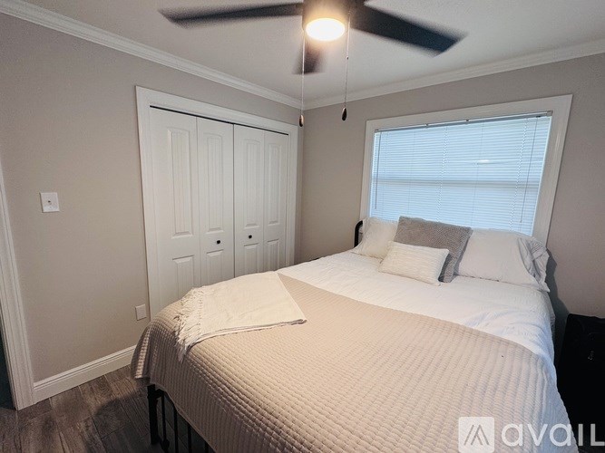 A bedroom with a bed, pillows, and a ceiling fan.
