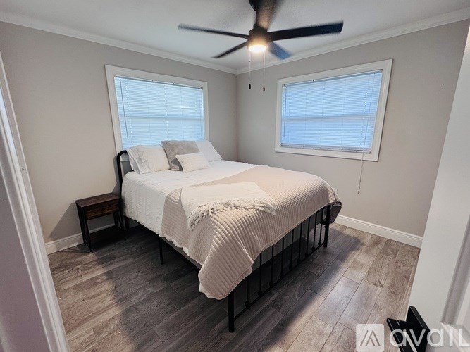 A bedroom with a bed, a ceiling fan, and a window with blinds.