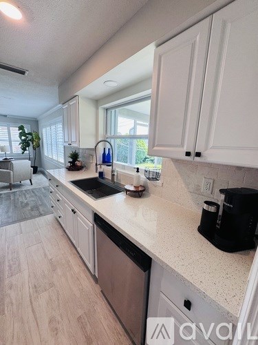 A kitchen with white cabinets and a black coffee maker on the counter.