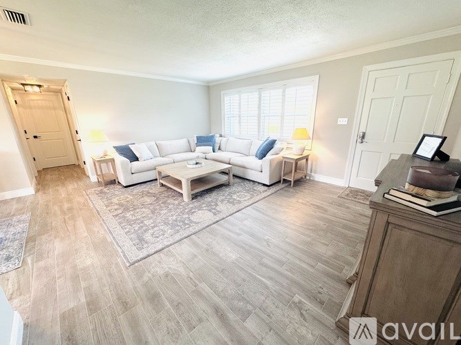 A living room with a white couch and a wooden floor.
