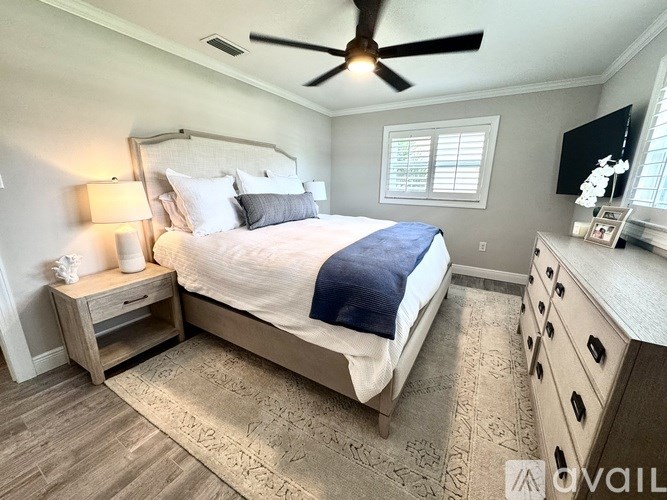 A bedroom with a large bed, a ceiling fan, and a dresser.