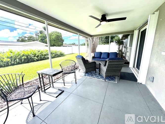A patio with a table, chairs and a ceiling fan.