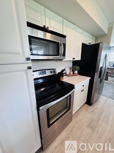 A kitchen with white cabinets and a black fridge.