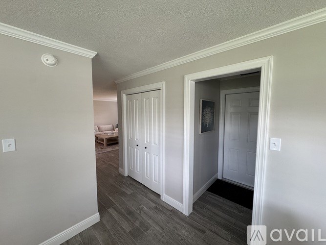 A hallway with a door on the right and a wall-mounted light fixture.