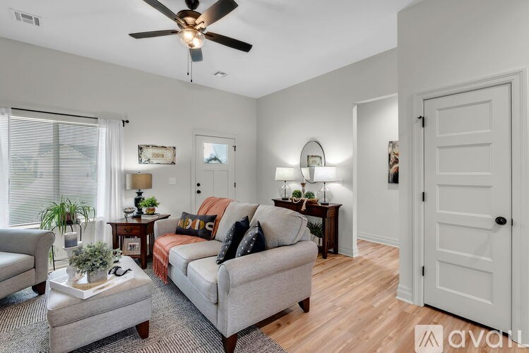 A living room with a grey couch, a coffee table, and a ceiling fan.