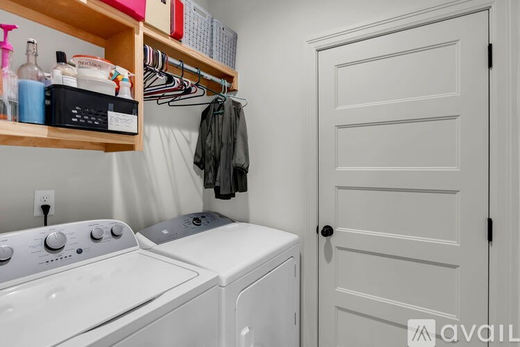 A laundry room with a washer and dryer, a coat hanging up, and a white door.