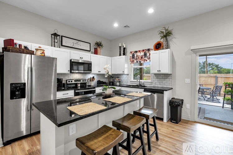 A kitchen with a refrigerator, stove, and bar stools.